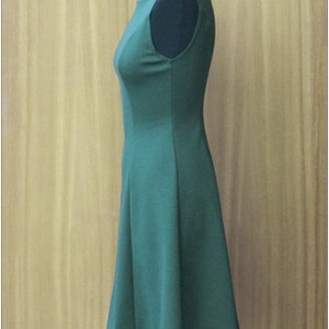 May include: A sleeveless, knee-length dress in a dark green color. The dress has a fitted bodice and a slightly flared skirt.