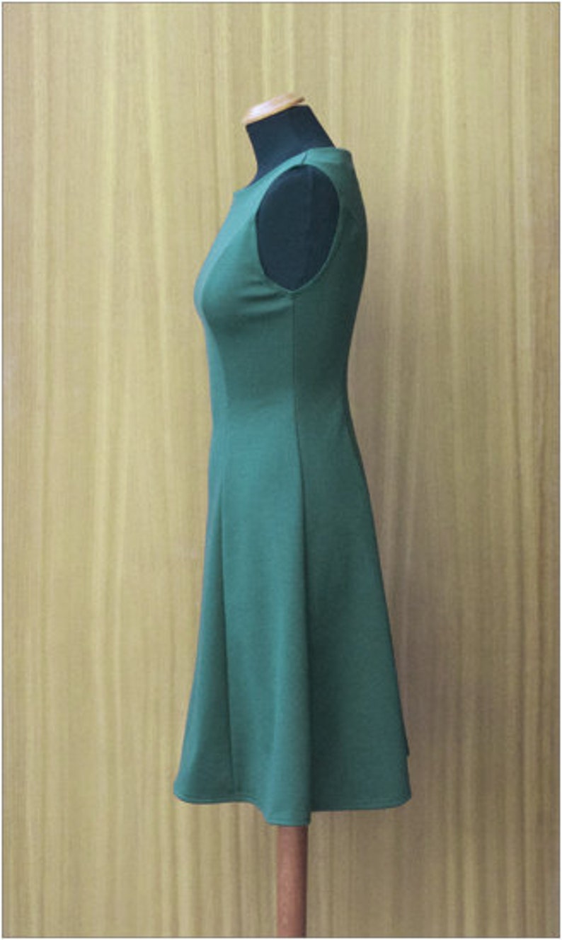 May include: A sleeveless, knee-length dress in a dark green color. The dress has a fitted bodice and a slightly flared skirt.