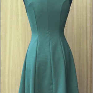 May include: A sleeveless, dark green dress with a fitted bodice and a flared skirt. The dress has a simple, elegant design.