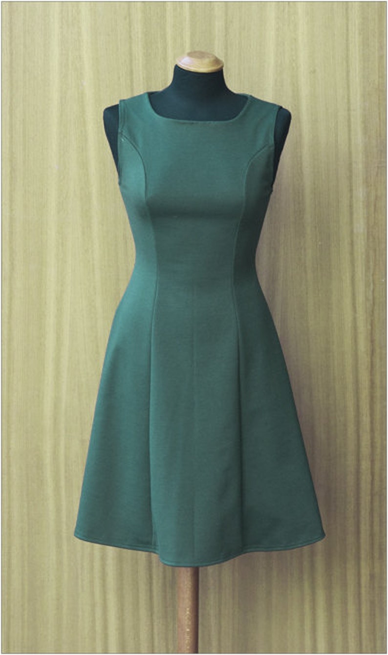 May include: A sleeveless, dark green dress with a fitted bodice and a flared skirt. The dress is on a mannequin against a woodgrain background.