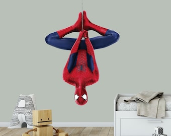Op de afbeelding: Een rode en blauwe Spiderman-muursticker die ondersteboven hangt aan een plafondhaak. De sticker is in een superheldenpose met uitgestrekte armen en benen.