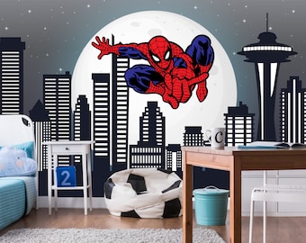 Pode incluir: Um mural de cidade em preto e branco com um personagem de Homem-Aranha vermelho e azul balançando na frente de uma lua cheia. O mural está em uma parede em um quarto com uma cama, uma mesa e uma cadeira.