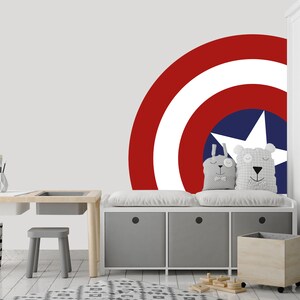 May include: A white, gray, and wood children's desk and bench set with a red, white, and blue Captain America shield decal on the wall behind it.