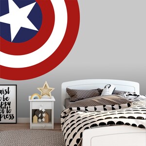 May include: A white bed with a black and white patterned duvet cover and a red, white, and blue Captain America shield wall decal. The bed is in a room with a white nightstand and a framed print with the text "Exist to be happy, not to impress".