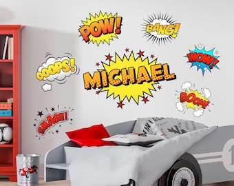 May include: A child's bedroom with comic book-style wall decals. The decals include words like "POW!" and "MICHAEL" in bold, colorful fonts. A race car bed and a red bookshelf are also visible.