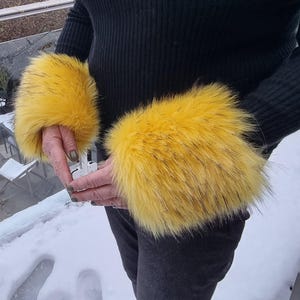 May include: A pair of yellow faux fur arm warmers. The arm warmers are soft and fluffy and would be perfect for keeping warm in the winter.