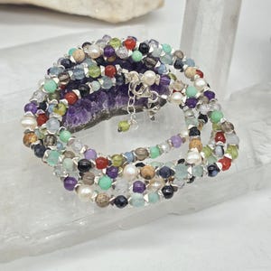 Puede incluir: Collar multi-cadena con una variedad de cuentas de piedras preciosas de colores, incluyendo amatista, aguamarina, cornalina y aventurina verde. El collar está hecho con cuentas de plata y un cierre de plata.