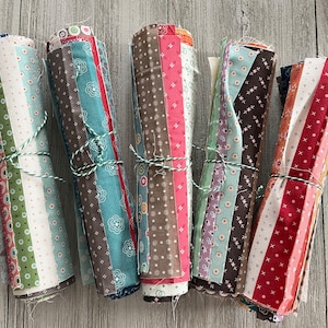 May include: Six bundles of fabric scraps, each tied with twine. The fabric scraps are in various patterns and colors, including brown, blue, pink, red, and white.