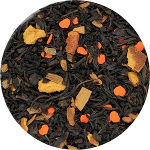 Könnte beinhalten: Nahaufnahme von schwarzen Teeblättern mit orangen und braunen Frucht- und Gewürzstücken.