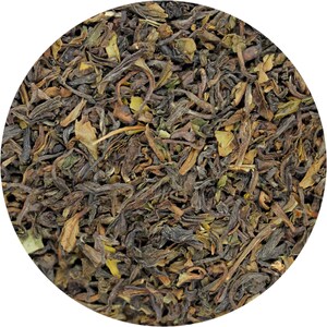 May include: Close-up of loose leaf black tea with a dark brown and green colour. The tea leaves are dried and ready to be brewed.