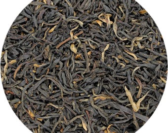 May include: Close-up of loose-leaf tea, featuring dark brown and black leaves with lighter, golden-brown tips. The tea leaves are tightly curled and appear dry, suggesting a high-quality tea product. The image is set against a white background.
