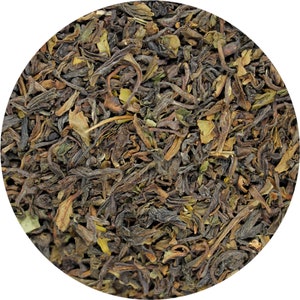 May include: Close-up of loose leaf black tea with a dark brown and green color. The tea leaves are dried and ready to be brewed.