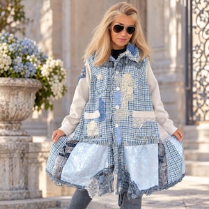 Könnte beinhalten: Eine langärmelige Jacke mit einem Patchwork-Design aus blau-weißem Karostoff, hellblauem Blumenbrokat und cremefarbenen Einsätzen. Das Kleidungsstück verfügt über ausgefranste Kanten, weiße Knöpfe, Spitzenapplikationen und einen strukturierten Saum.