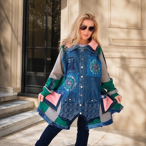 Peut inclure: Une veste en jean à manches longues avec un design patchwork composé de panneaux en jean bleu, jersey gris et tissu vert. La veste présente des poches roses, des broderies florales bleues, une fermeture boutonnée et un ourlet en dentelle.