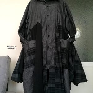 Könnte beinhalten: Ein Patchwork-Kleidungsstück aus verschiedenen grau-schwarzen gestreiften und karierten Hemden. Das Design umfasst einen Kragen, eine Knopfleiste, Taschen und eine lange, fließende Silhouette. Der Text "Designed by MARTINELLI" ist sichtbar.