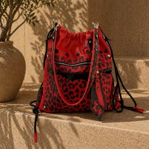 Può includere: Zaino con coulisse con stampa leopardata rossa e nera con dettagli neri. La borsa ha una tasca frontale con cerniera, coulisse nere e un'etichetta decorativa. La borsa è realizzata in materiale simile alla pelle.