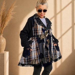 Peut inclure: Un manteau patchwork avec un mélange de tissus à carreaux, floraux et unis en marine, marron et crème. Le manteau a un col noir avec une bordure en dentelle, des manches longues noires et des poches. L'ourlet est fini avec de la dentelle noire.