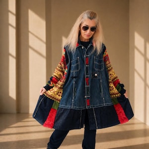 Könnte beinhalten: Jeansjacke mit bunten gemusterten Ärmeln und roten Akzenten. Die Jacke hat eine Knopfleiste vorne und einen ausgestellten Rock. Die Ärmel weisen eine Mischung aus roten, gelben und schwarzen Mustern auf. Die Jacke wird von einer Person mit Sonnenbrille getragen.