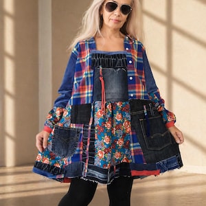 Op de afbeelding: Een patchwork tuniek met een mix van blauw geruit flanel, donkere denim panelen en een levendige bloemenprint. Het kledingstuk is voorzien van denim zakken, een knoopsluiting aan de voorzijde en een uitlopend silhouet, gecombineerd met een zwarte legging.