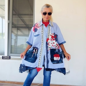 May include: A light blue patchwork shirt with denim pockets and floral accents. The shirt features a mix of fabrics, including denim and floral prints, with lace trim and the text "Designed by MARTINELLI".