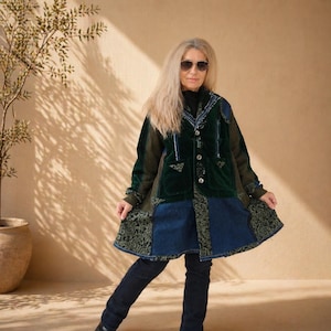 Könnte beinhalten: Eine langärmelige Jacke mit einem Patchwork-Design aus dunkelgrünem Samt, blauem Denim und schwarzem Stoff mit einem sich wiederholenden Blumenmuster. Die Jacke hat eine Knopfleiste, einen Kragen und zwei Vordertaschen, kombiniert mit einer dunkelblauen Jeans.