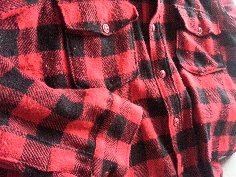 May include: Red and black plaid flannel shirt with a button-up front and two pockets.