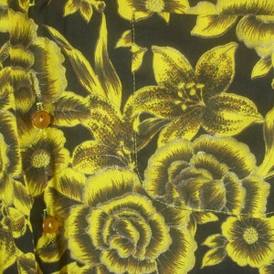 May include: A black fabric with a yellow floral pattern. The fabric has a shiny, almost metallic, finish. The flowers are lilies and roses.