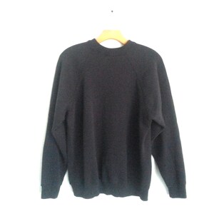 May include: A dark gray long-sleeved sweater with a crew neck and raglan sleeves.