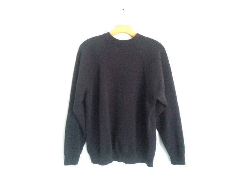 May include: A dark gray long-sleeved sweater with a crew neck and raglan sleeves.