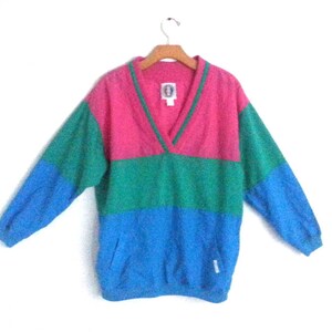 May include: A pink, green, and blue striped sweater with a v-neck and long sleeves.