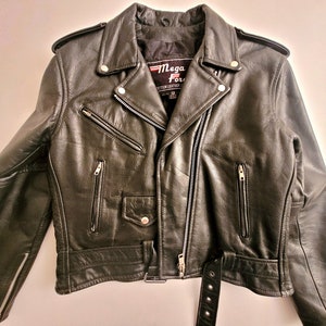 May include: Black leather motorcycle jacket with a zipper closure, multiple pockets, and a belt. The jacket has a label that reads "Mega Force" with a small American flag.