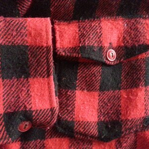 May include: Red and black plaid flannel shirt with a patch pocket and two buttons.