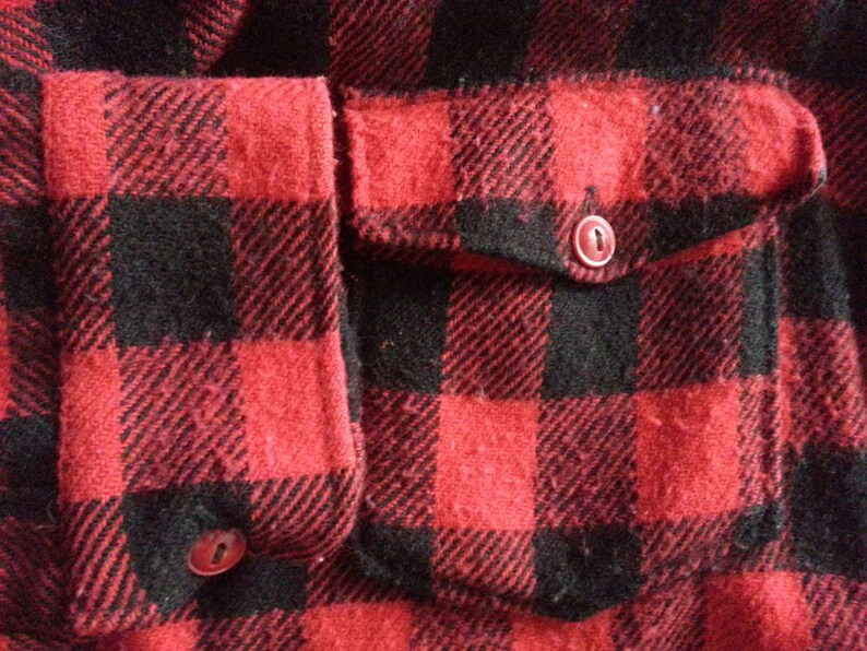 May include: Red and black plaid flannel shirt with a patch pocket and two buttons.