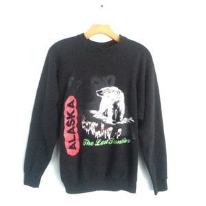 May include: Black sweatshirt with a white polar bear graphic and the text "ALASKA The Last Frontier" in red and green.