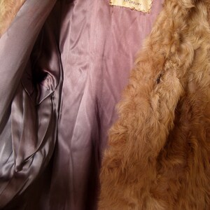 May include: The inside of a brown fur coat with a satin lining. The lining is a light purple color. The label on the coat reads "Waterbury".