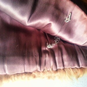 May include: The inside of a brown fur coat with a pink satin lining. The lining has two small holes in it.