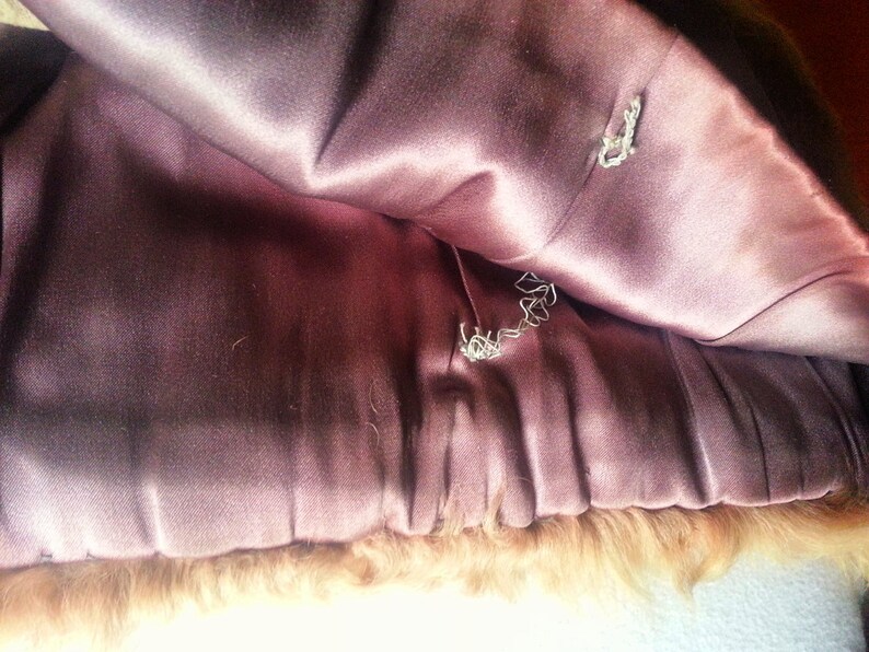 May include: The inside of a brown fur coat with a pink satin lining. The lining has two small holes in it.