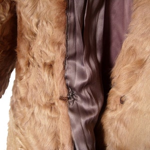 May include: A brown fur coat with a satin lining. The coat is open and the lining is visible. The fur is soft and fluffy.