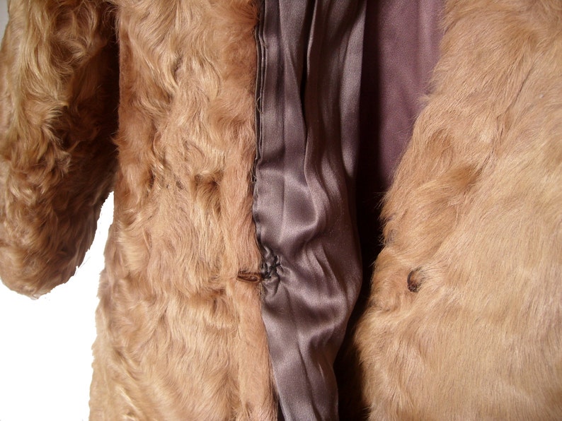 May include: A brown fur coat with a satin lining. The coat is open and the lining is visible. The fur is soft and fluffy.