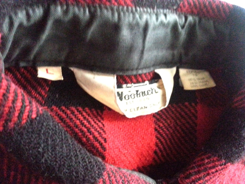 May include: Red and black plaid flannel shirt with a black collar and a white label that says "Woolrich" and "Clifan, Inc."