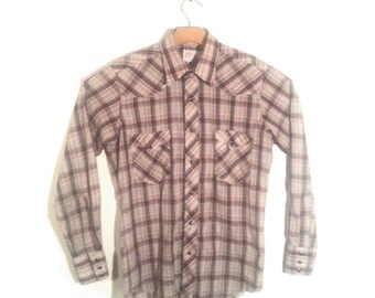 May include: A long-sleeved plaid shirt with a button-down collar and pearl-like buttons. The shirt has two chest pockets with button closures and a brown and white plaid pattern.