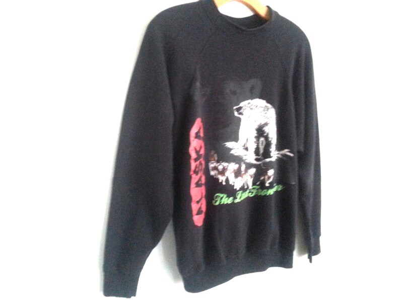May include: Black sweatshirt with a graphic print of a polar bear and other animals. The text "Alaska The Last Frontier" is printed on the sweatshirt.