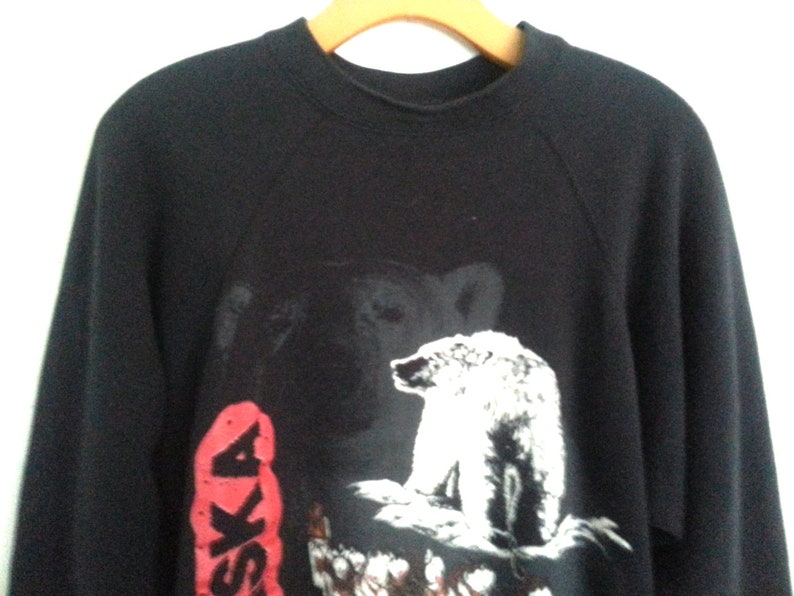 May include: Black sweatshirt with a white polar bear and the word "Alaska" in red on the front.