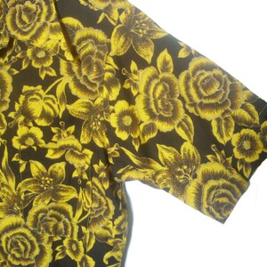 May include: A short-sleeved shirt with a black background and a yellow floral pattern.