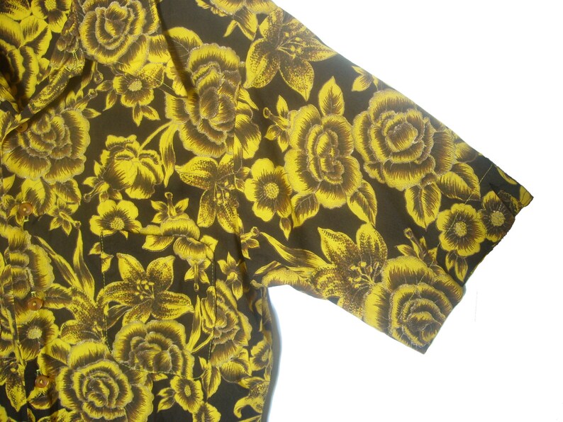 May include: A short-sleeved shirt with a black background and a yellow floral pattern.