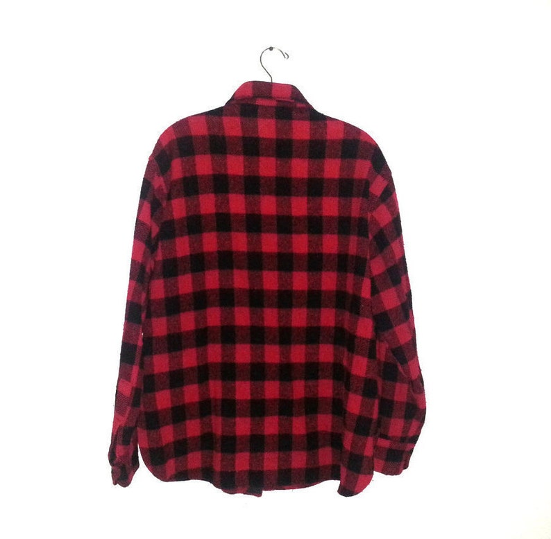 May include: A red and black plaid flannel shirt with long sleeves and a button-up front.