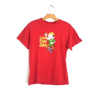 May include: Red short-sleeved t-shirt with a cartoon character and the text "Less Than Jake" printed on the front.