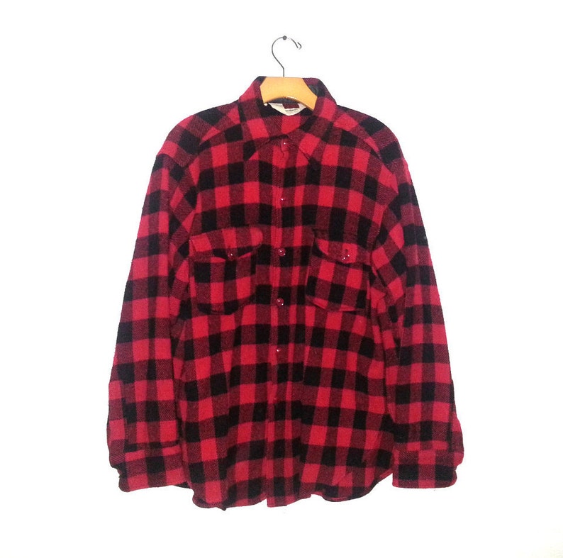 May include: A red and black plaid flannel shirt with long sleeves and two chest pockets.