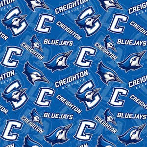 May include: A blue and white fabric pattern featuring the Creighton Bluejays logo, the letter "C", and the words "Creighton Bluejays".