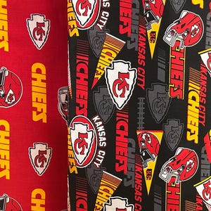 K&ouml;nnte beinhalten: Zwei Stoffrollen mit einem sich wiederholenden Muster des Kansas City Chiefs-Logos, Helmen und Text. Eine Rolle ist rot, die andere ist schwarz. Die Logos sind wei&szlig;, rot und gelb.